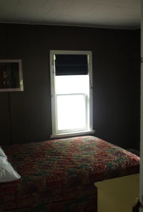 Pigeon Lake Resort Cottage Two.&nbsp; Bedroom with a bed beside a window in a cottage interior.